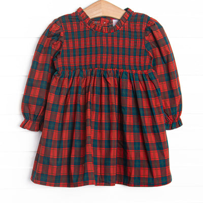  This dress features red plaid fabric, chest smocking, and long sleeves. 