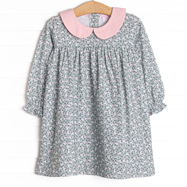  This dress features a green floral print, pink peter pan collar, and button closure on the back. 