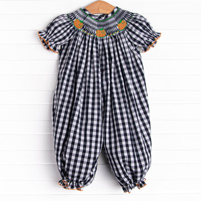 This romper features a navy check print, puff sleeves, and pumpkin smockings