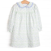 This dress features a floral print, a peter pan collar with blue ruffle trim, and button closure on the back.
