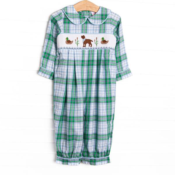  This romper features a blue plaid print, snaps on the stride, and a dog and mallard smocking. 