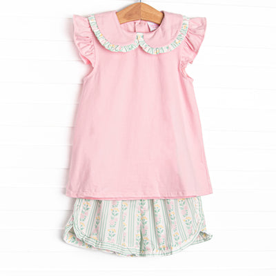 This set features a pink flutter sleeve top with a peter pan collar and ruffle trim. Coordinating green floral shorts with a bow detail to match.