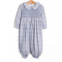 This romper features a blue floral print, a peter pan collar, and a dainty floral smocking.