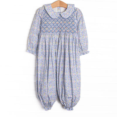 This romper features a blue floral print, a peter pan collar, and a dainty floral smocking.