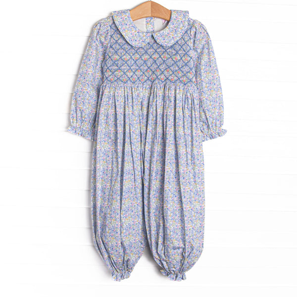 This romper features a blue floral print, a peter pan collar, and a dainty floral smocking.