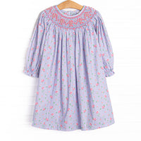 This dress features a blue floral print, button closure on the back, and a dainty floral smocking.