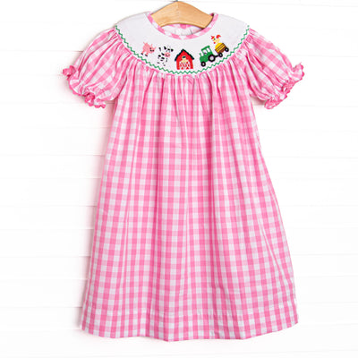  This dress features a pink check material, farm smocking, and short puff sleeves with ric rac trim. 