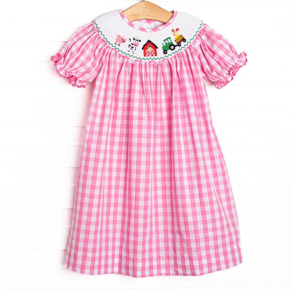  This dress features a pink check material, farm smocking, and short puff sleeves with ric rac trim. 