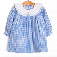  This dress features blue gingham fabric, a white eyelet lace trimmed collar, and long sleeves. 