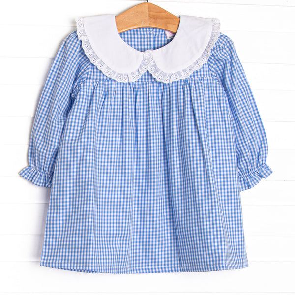 This dress features blue gingham fabric, a white eyelet lace trimmed collar, and long sleeves. 