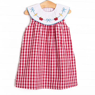 This dress features a red check print, a bib collar and a dainty school embroidery.