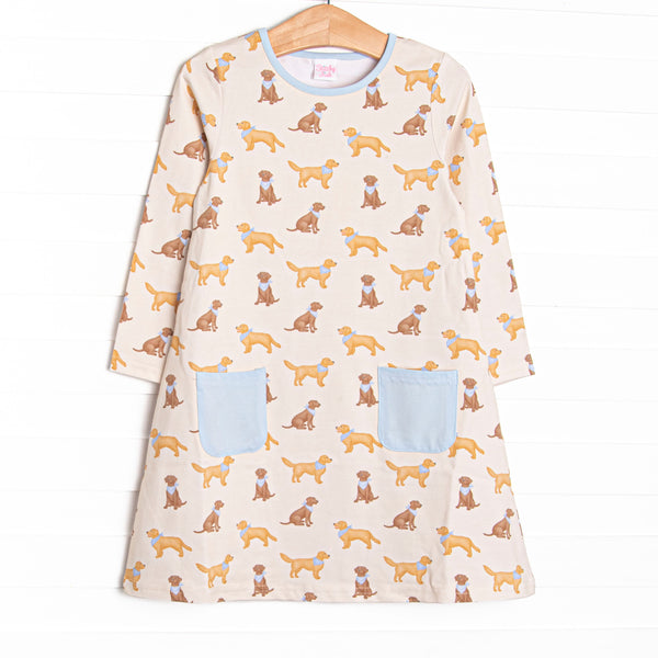  This yellow dress features golden retriever printed fabric, a blue front pockets, and blue trim. 