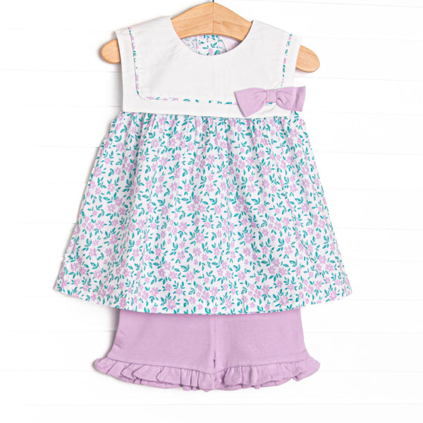 This set features a blue floral print, a scalloped bib collar, and purple ruffle shorts to match.
