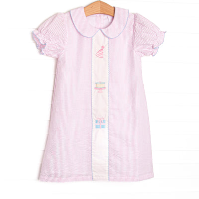 This birthday dress features light pink seersucker fabric, birthday embroidery, a pink Peter Pan collar, and short puff sleeves.