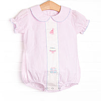 This birthday bubble features light pink seersucker fabric, birthday embroidery, a pink Peter Pan collar, and short puff sleeves.
