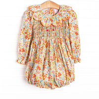  This smocked bubble features floral print, a scalloped collar, and long sleeves. 