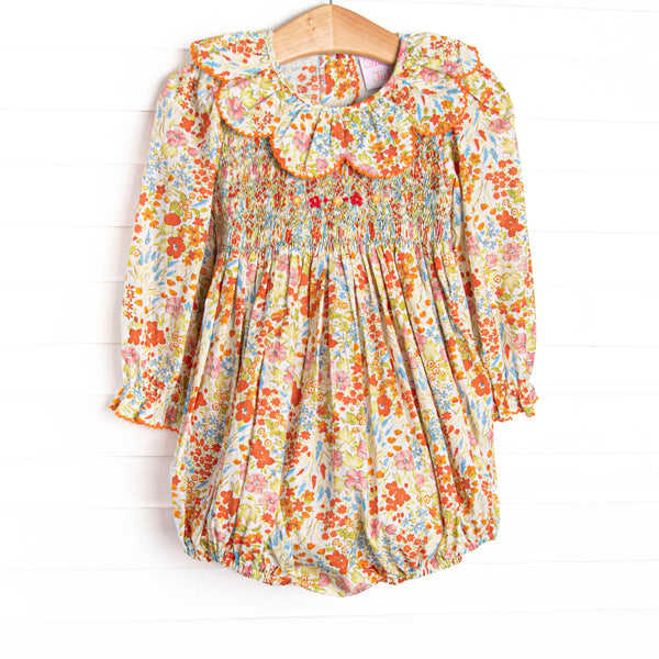  This smocked bubble features floral print, a scalloped collar, and long sleeves. 