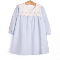  This dress features a blue gingham top, a bib collar, and bows and flowers appliques. 