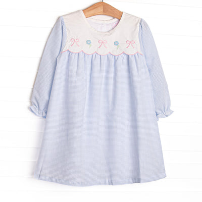  This dress features a blue gingham top, a bib collar, and bows and flowers appliques. 