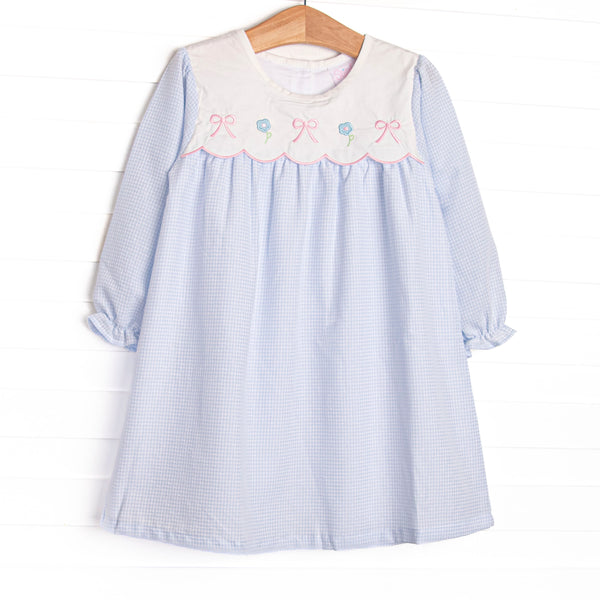  This dress features a blue gingham top, a bib collar, and bows and flowers appliques. 