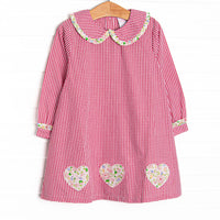  This dress features a red mini gingham print, a peter pan collar with ruffle trim, and floral heart appliques. 