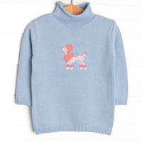 This sweater features blue knit material, a pink poodle icon, and a rolled neck.
