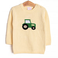 This sweater features a yellow knit material, buttons on the shoulders, and a tractor icon. 