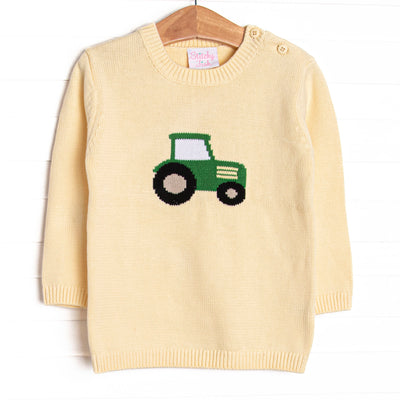 This sweater features a yellow knit material, buttons on the shoulders, and a tractor icon. 
