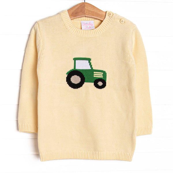 This sweater features a yellow knit material, buttons on the shoulders, and a tractor icon. 