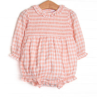 This bubble features a pink gingham print, ruffle collar, and elastic smocking across the chest!