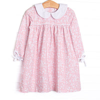  This dress features a pink floral print, white ruffle trim, and a white Peter Pan collar. 