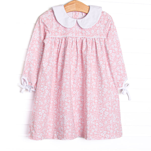  This dress features a pink floral print, white ruffle trim, and a white Peter Pan collar. 