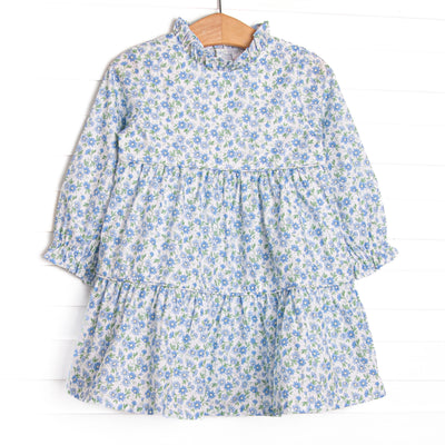  This dress features a blue floral print, a ruffle neck collar, and tiered ruffles. 