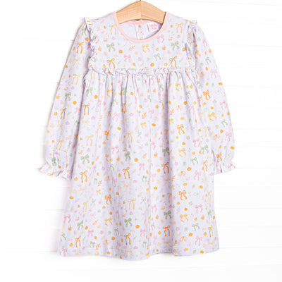  This dress features a pink pumpkin and bow print, ruffle neck trim, and long sleeves. 