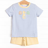  This set features a top in a blue striped print, a seahorse applique, and yellow shorts to match. 