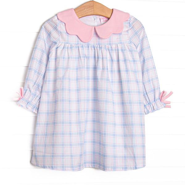  This dress features a blue and pink plaid fabric, a pink scalloped collar, and pink sleeve ties. 