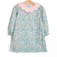  This dress features a green floral print, a pink petal collar, and button closure on the back. 