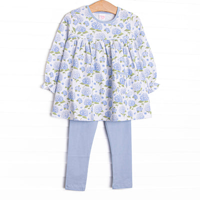 This set features a long sleeve top in a blue hydrangea print, blue trim, and a front pocket. Coordinating blue knit leggings to match.