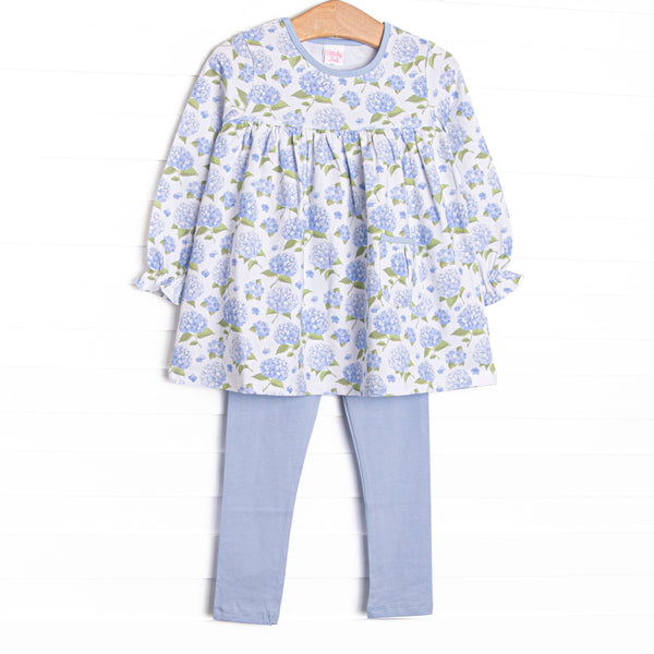 This set features a long sleeve top in a blue hydrangea print, blue trim, and a front pocket. Coordinating blue knit leggings to match.