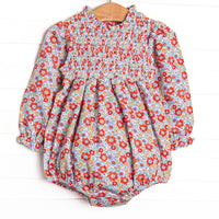 This bubble features a red floral print, chest smocking, and long sleeves.