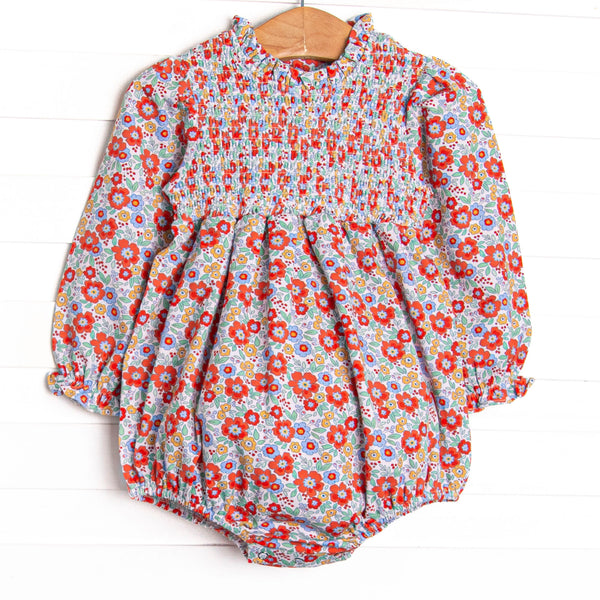 This bubble features a red floral print, chest smocking, and long sleeves.