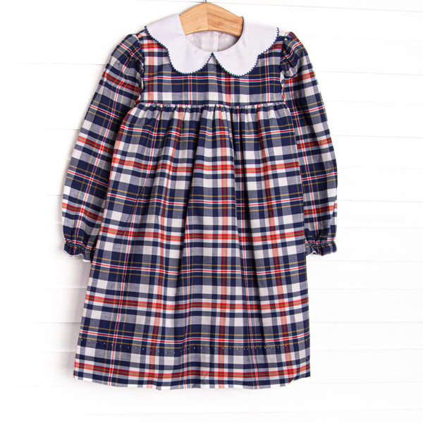 This dress features a navy and red plaid fabric, a scalloped collar, and long sleeves.