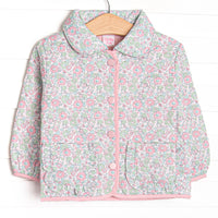  This coat features a green floral quilted material, a peter pan collar, and pink buttons. 