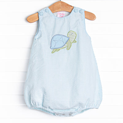  This bubble features a mint green seersucker print, front covered buttons, and a turtle applique. 