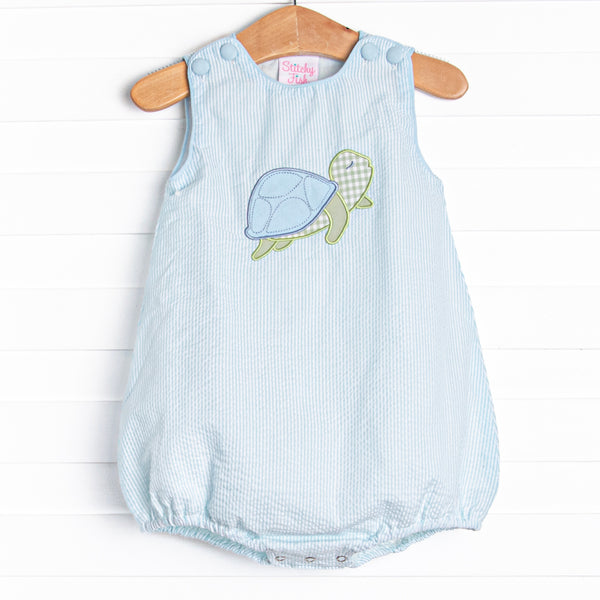 This bubble features a mint green seersucker print, front covered buttons, and a turtle applique. 