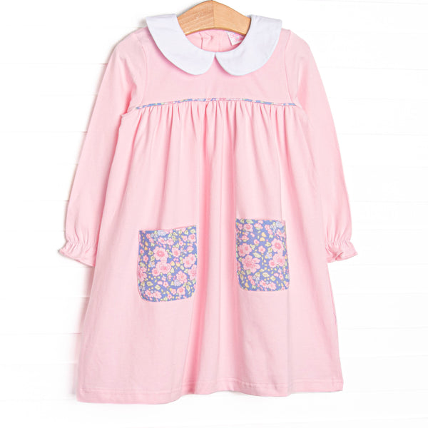 This dress features a pink knit material, purple floral front pockets, and peter pan collar.