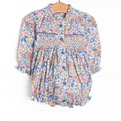 This bubble features a navy floral fabric, dainty smocking, and front buttons.