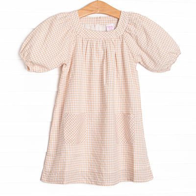  This dress features tan gingham fabric, puff sleeves, and front pockets. 