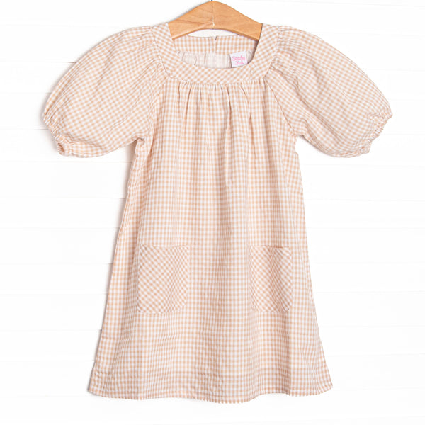 This dress features tan gingham fabric, puff sleeves, and front pockets. 