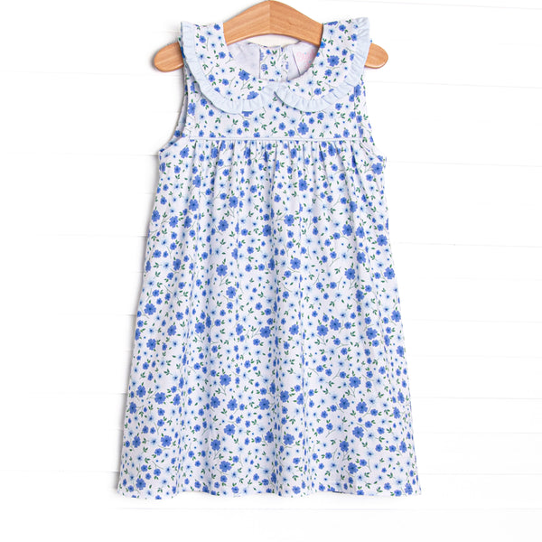 The dress features a peter pan collar, ruffle trim, and a vibrant blue floral print.